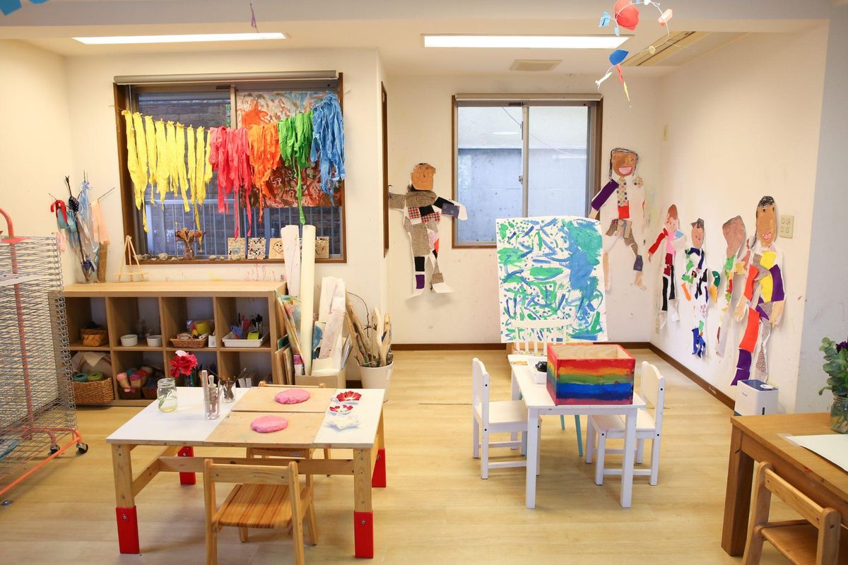 カラフルな染め布が飾られたアートルームで制作に取り組む様子