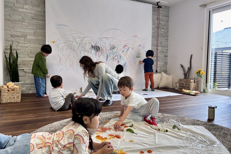 大きな紙いっぱいに、みんなで絵を描く子どもたちと先生