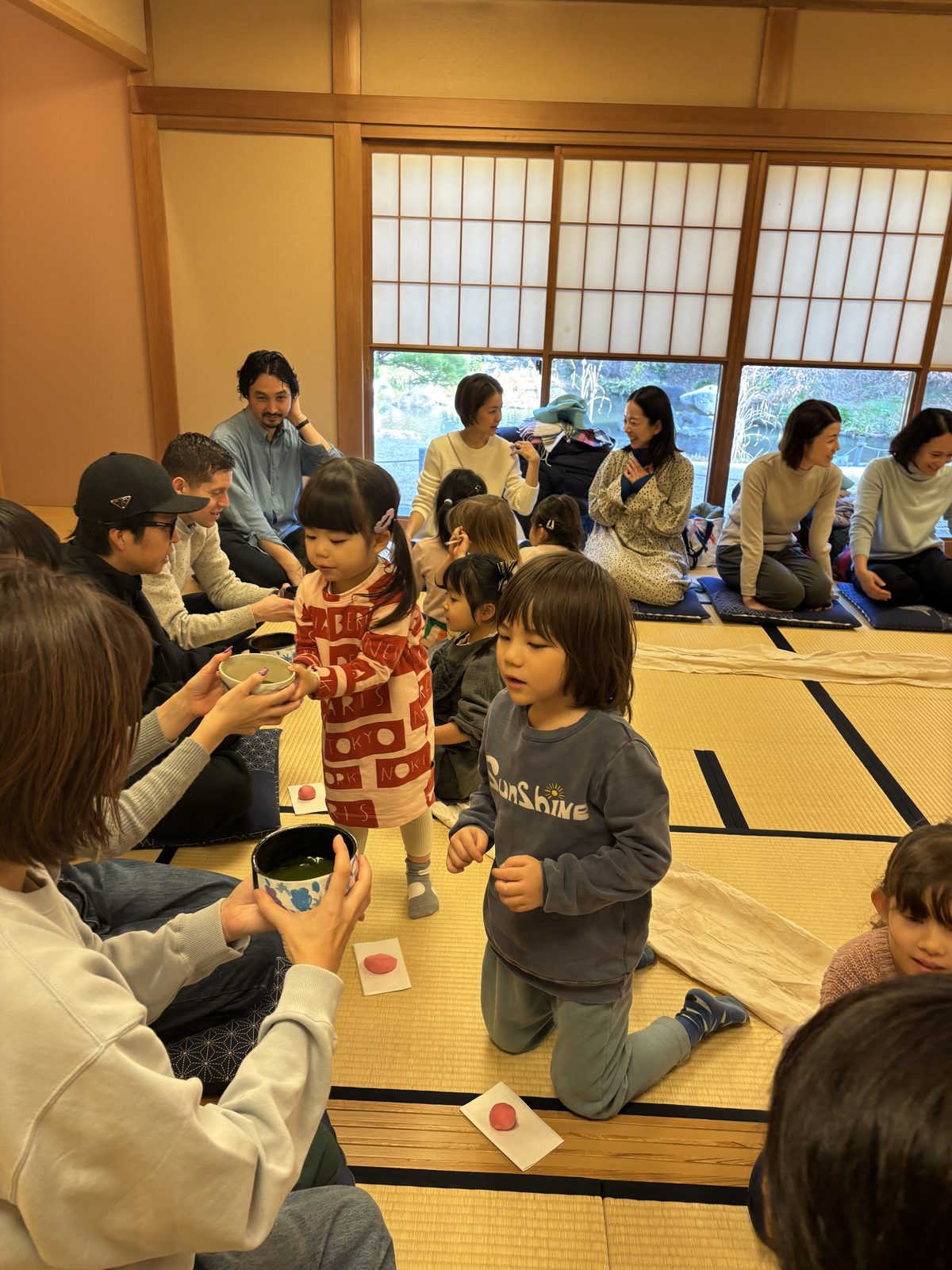 畳の部屋で、保護者と子どもたちがお茶をいただく茶道イベントの様子