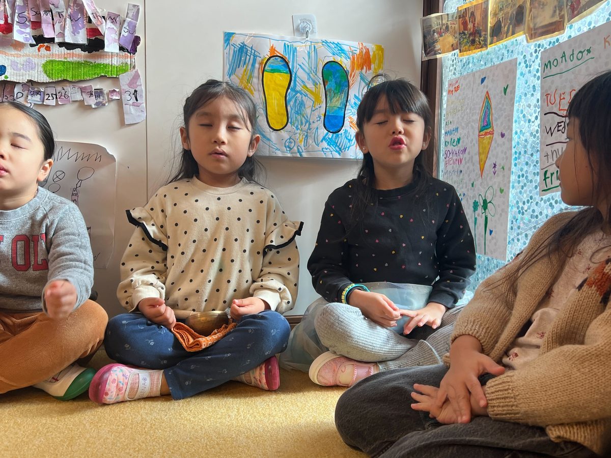 輪になって座り、静かに目を閉じて呼吸を整える子どもたち