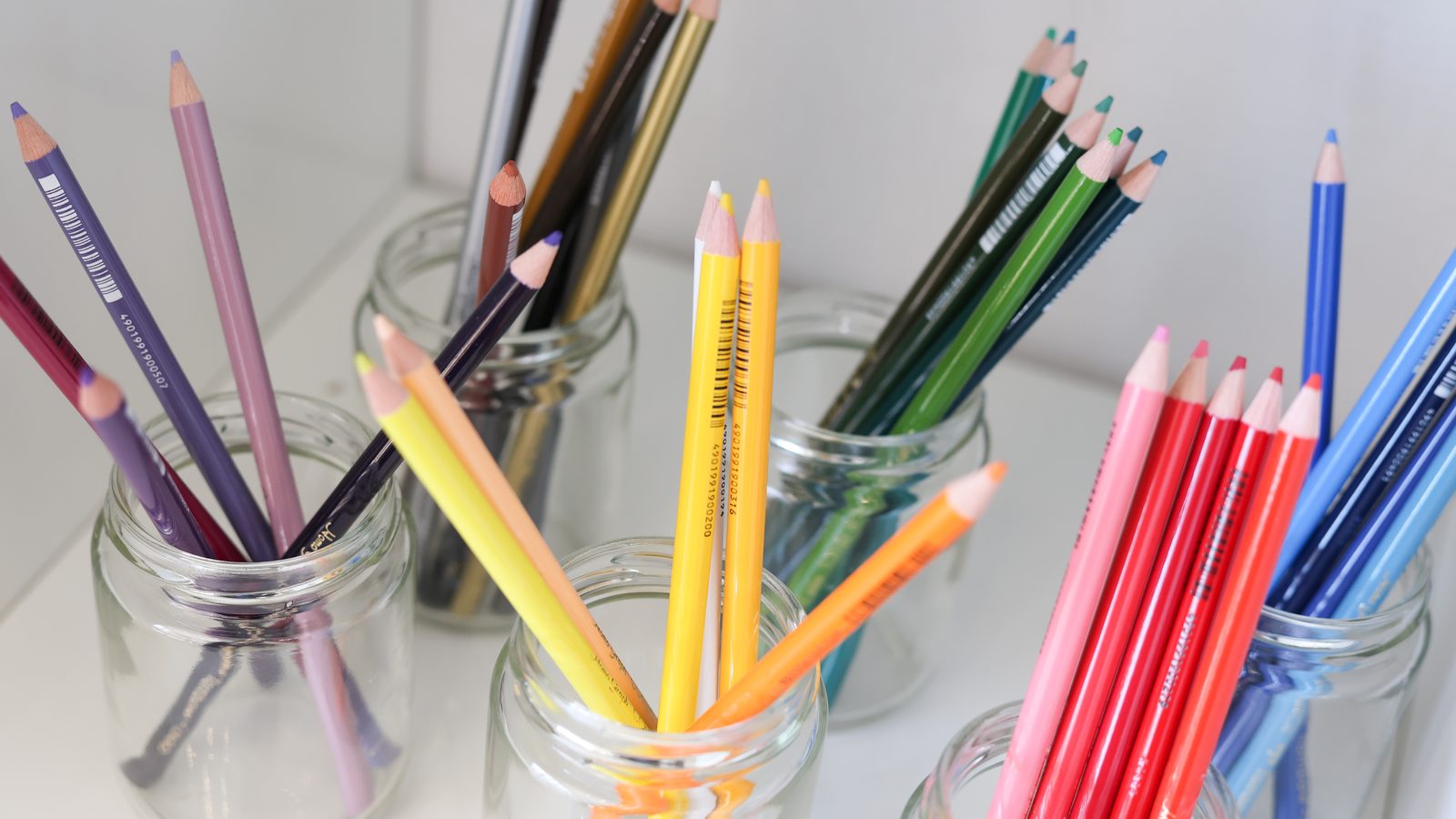 Colorful pencils sorted by color in glass jars
