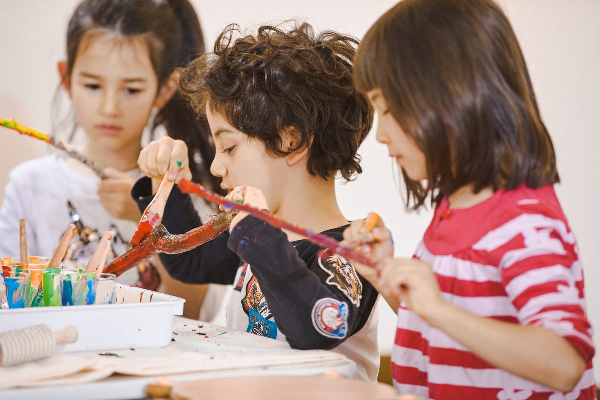 Children making big, dynamic art with branches and paint