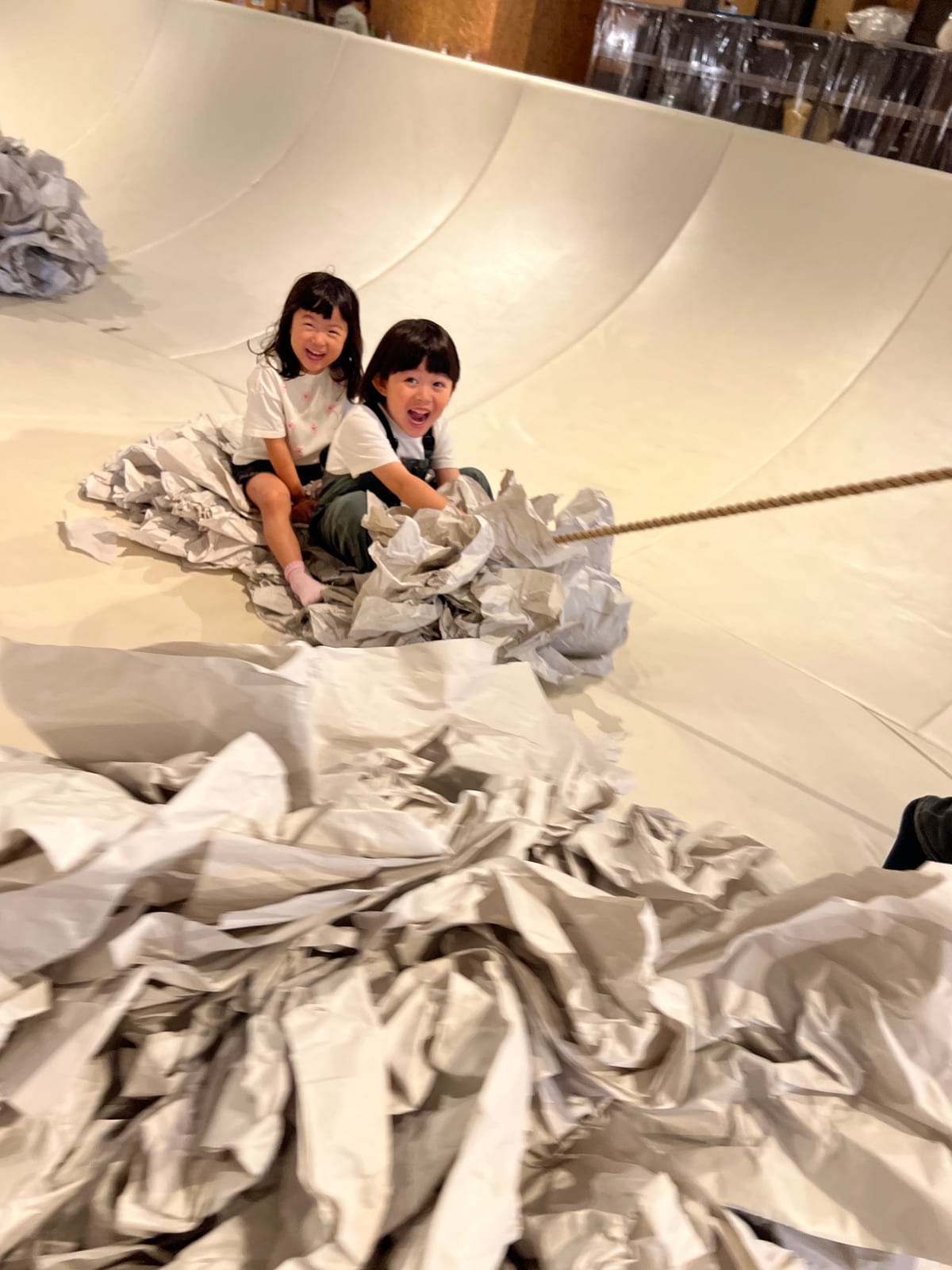 紙の山の中で、二人でロープを引っ張る子どもたち