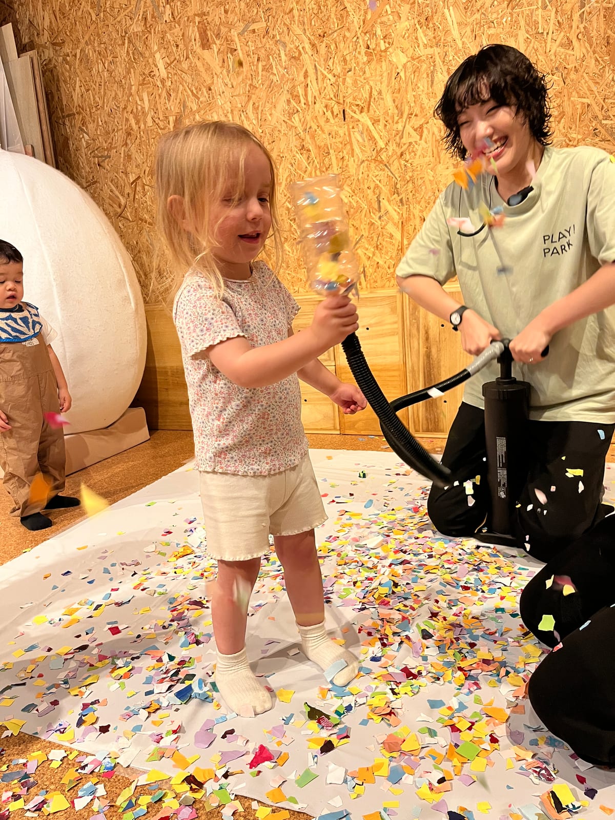 空気入れを押して、紙吹雪シューターから紙吹雪を飛ばす子ども